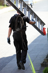 Image showing Chimney sweep carrying an extension ladder