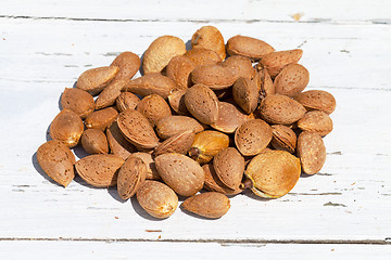 Image showing Almonds unpeeled nuts on white wooden background