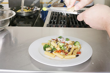 Image showing Italian food. Chef putting parmesan over a rigatoni with vegetab