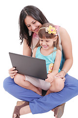 Image showing Young mother and daughter looking at laptop.  Focus in the mothe