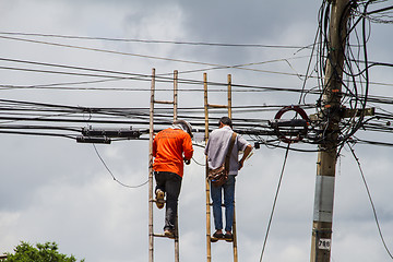 Image showing lineman working on cable - telephone pole from ladder