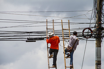 Image showing lineman working on cable - telephone pole from ladder