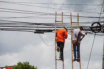 Image showing lineman working on cable - telephone pole from ladder