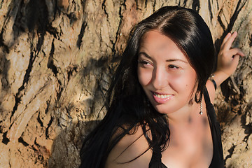 Image showing The girl near a tree trunk