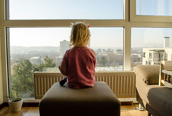 Image showing girl pink sweater sit settee before large window 