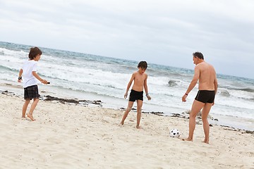 Image showing happy family father two kids playing football on beach summer 