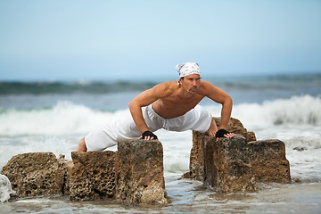 Image showing healthy man doing pilates yoga meditation on beach summer