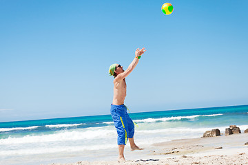 Image showing attractive young man playing volleyball on the beach