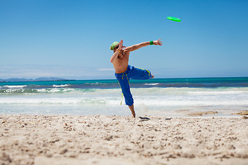 Image showing attractive man playing frisby on beach in summer