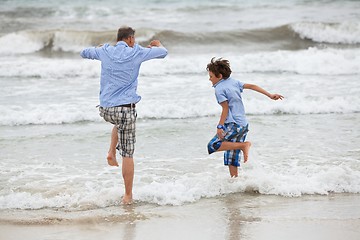 Image showing father and sons on the beach playing in the sand