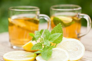 Image showing fresh tasty hot tea lemon and mint outdoor in summer 