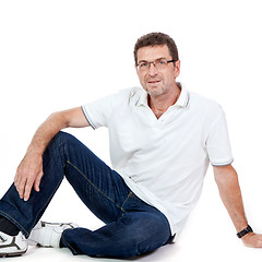 Image showing attractive healthy adult man sitting on floor with jeans isolated