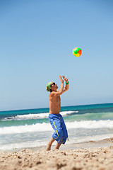 Image showing attractive young man playing volleyball on the beach