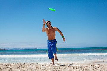 Image showing attractive man playing frisby on beach in summer