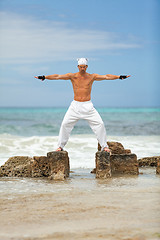 Image showing healthy man doing pilates yoga meditation on beach summer