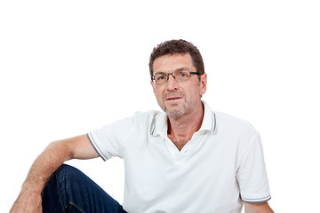 Image showing attractive healthy adult man sitting on floor with jeans isolated