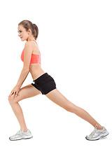 Image showing young attractive woman stretching legs after jogging isolated