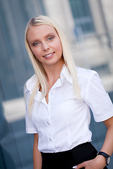 Image showing attractive young successful smiling business woman standing outdoor 