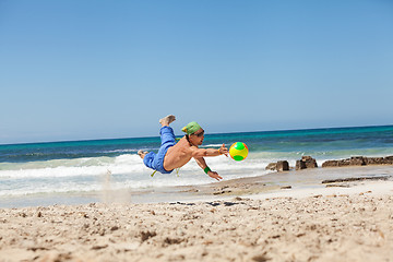 Image showing attractive young man playing volleyball on the beach