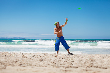 Image showing attractive man playing frisby on beach in summer