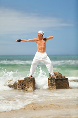 Image showing healthy man doing pilates yoga meditation on beach summer