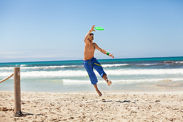 Image showing attractive man playing frisby on beach in summer