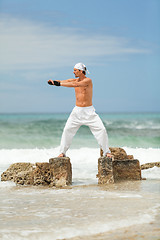 Image showing healthy man doing pilates yoga meditation on beach summer