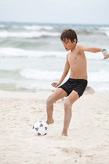 Image showing happy little boy  playing football on beach summer 