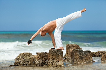 Image showing healthy man doing pilates yoga meditation on beach summer