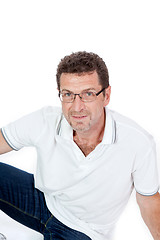 Image showing attractive healthy adult man sitting on floor with jeans isolated