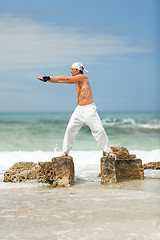 Image showing healthy man doing pilates yoga meditation on beach summer