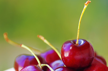 Image showing fresh cherries on table, green background