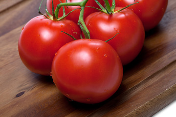 Image showing Bunch of fresh tomatoes with water drops on wooden cutting board