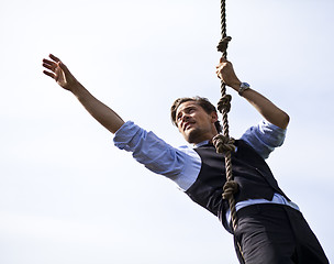 Image showing Determined businessman climbing a rope, reaching