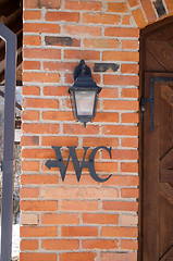 Image showing wc toilet sign symbol red brick wall retro lamp 