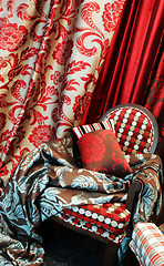 Image showing Luxurious red chair with satin pillows and curtains