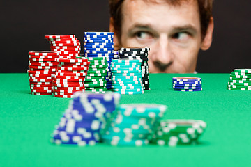 Image showing man looking under the table on playing chips