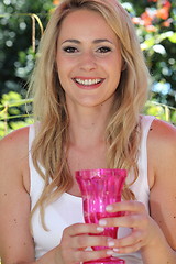 Image showing Smiling young woman holding a vase