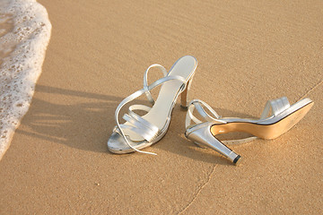 Image showing Ladies silver shoes on  a beach