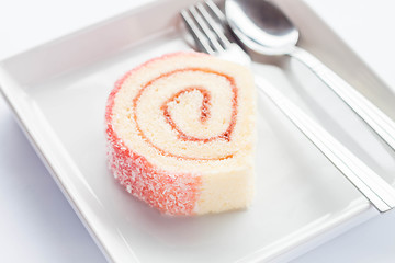 Image showing Pink jam roll cake with spoon and fork