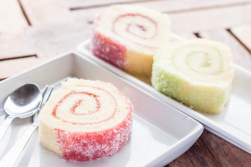 Image showing Colorful jam rolls on white dish with spoon and fork