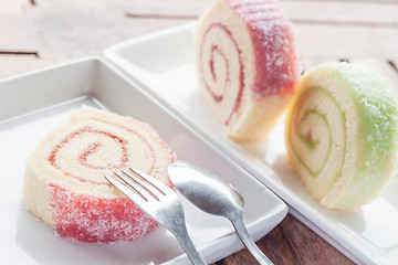 Image showing Slice of colorful jam roll on wood table