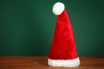 Image showing Red Santa Hat With Copy Space on Green and Wood Background