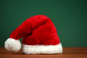 Image showing Red Santa Hat With Copy Space on Green and Wood Background