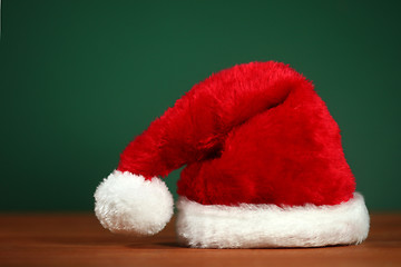 Image showing Red Santa Hat With Copy Space on Green and Wood Background