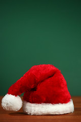 Image showing Red Santa Hat With Copy Space on Green and Wood Background