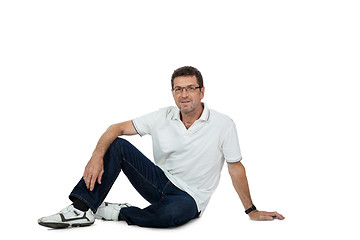 Image showing attractive healthy adult man sitting on floor with jeans isolated