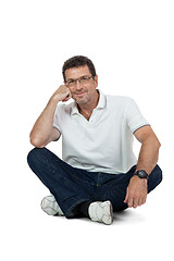 Image showing attractive healthy adult man sitting on floor with jeans isolated