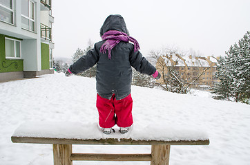 Image showing child with red pants standing wooden bench snow  