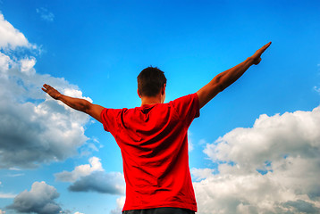 Image showing Young man staying with raised hands